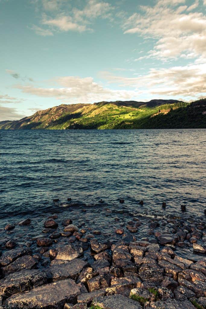 Loch Ness, a lake with rocks and green hills on the other side