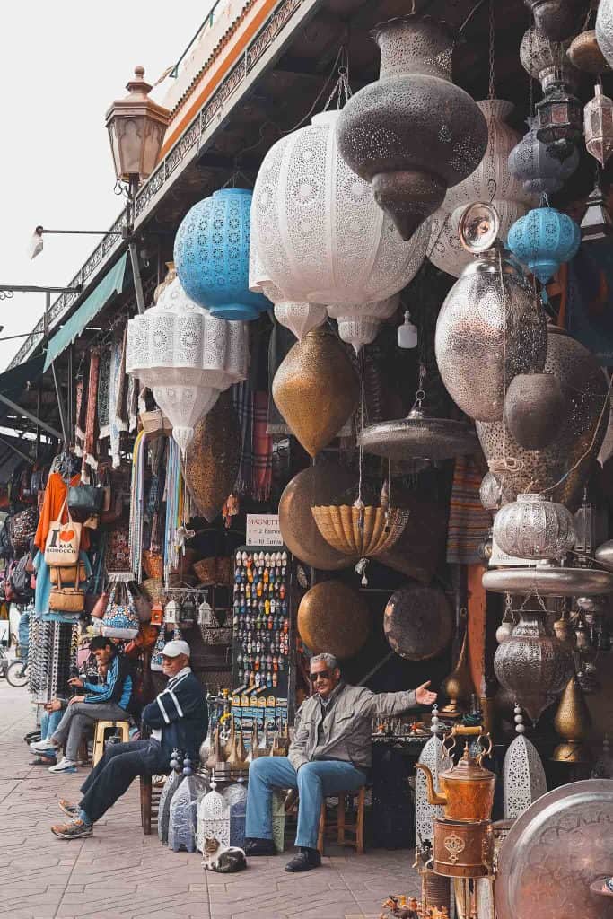 men sitting outside their shops in Morocco's souks with lanterns all around them on display